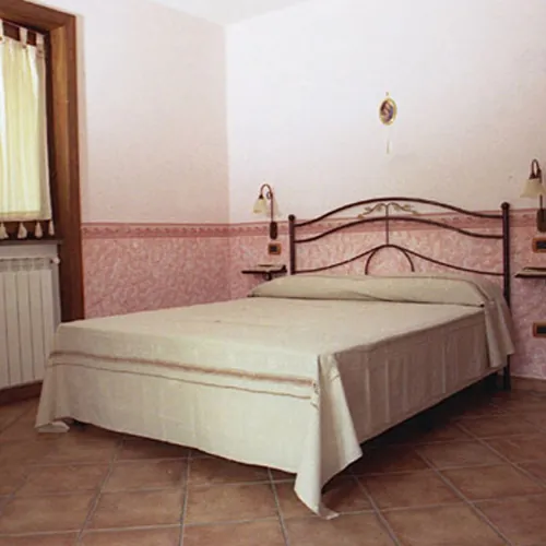 Camera con letto in ferro battuto e testata rosa